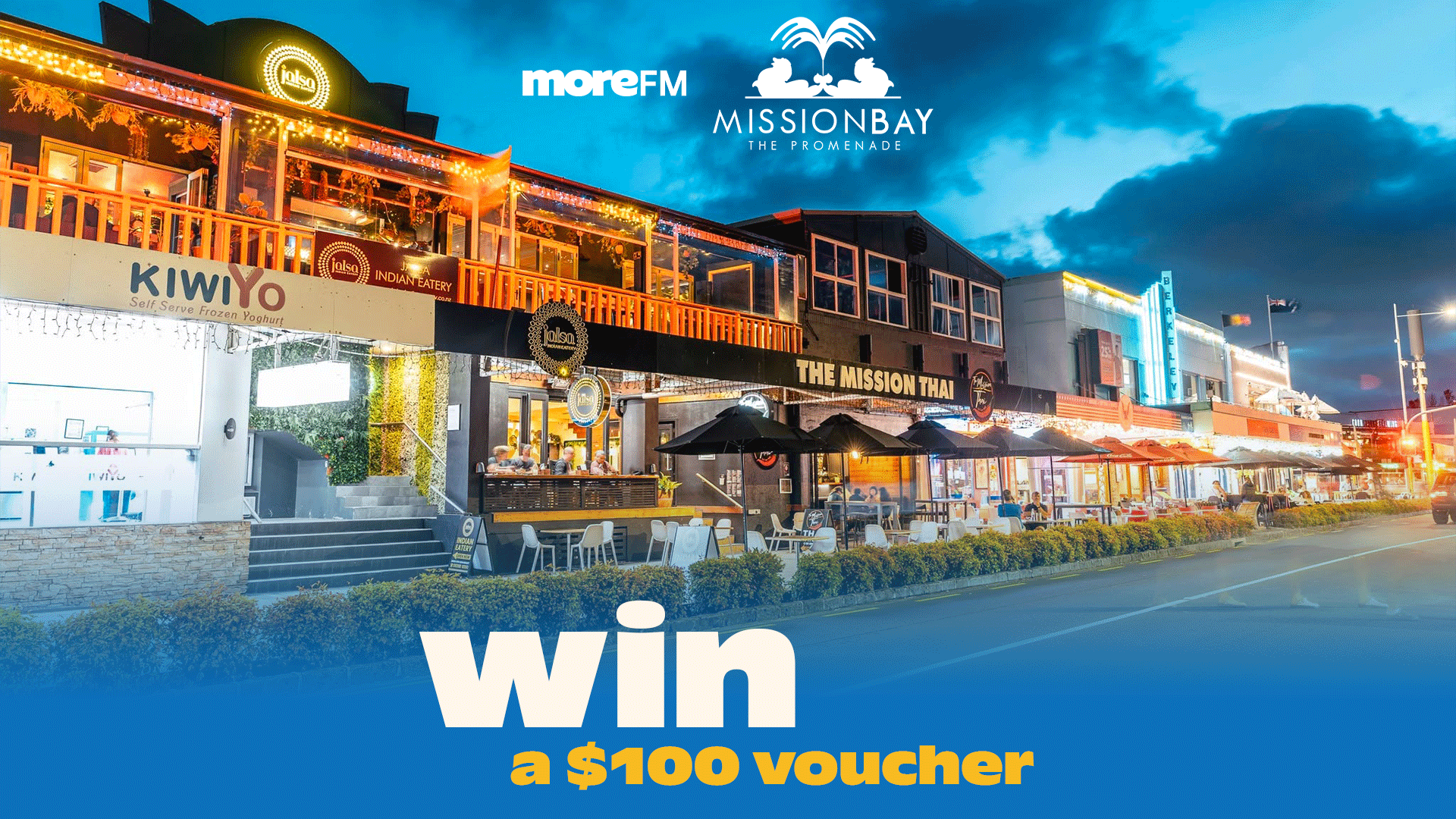 A nighttime view of a bustling street in Mission Bay, The Promenade, featuring restaurants like Jalsa and The Mission Thai, with "win a $100 voucher" text and sponsor logos.