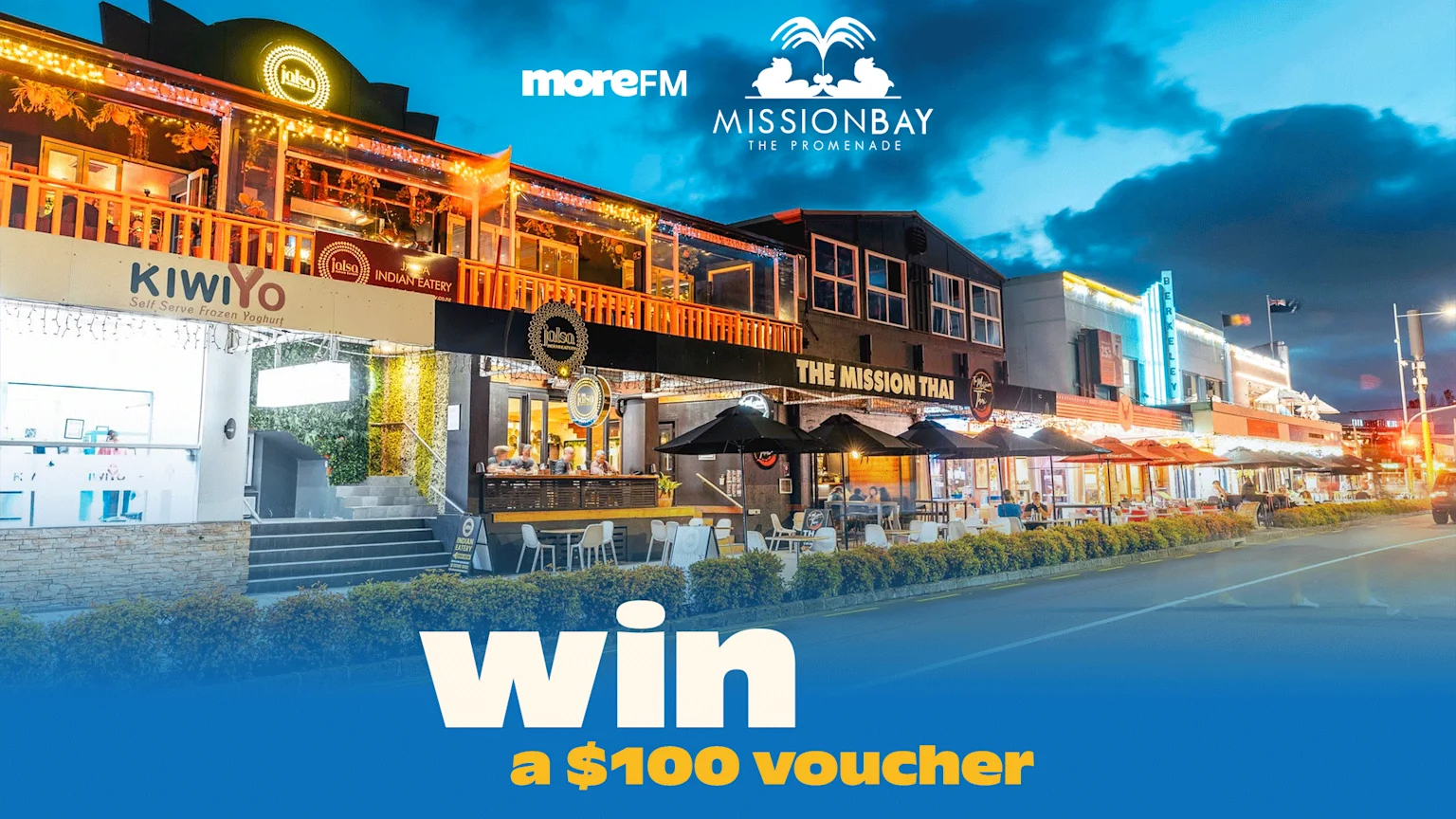A nighttime view of a bustling street in Mission Bay, The Promenade, featuring restaurants like Jalsa and The Mission Thai, with "win a $100 voucher" text and sponsor logos.