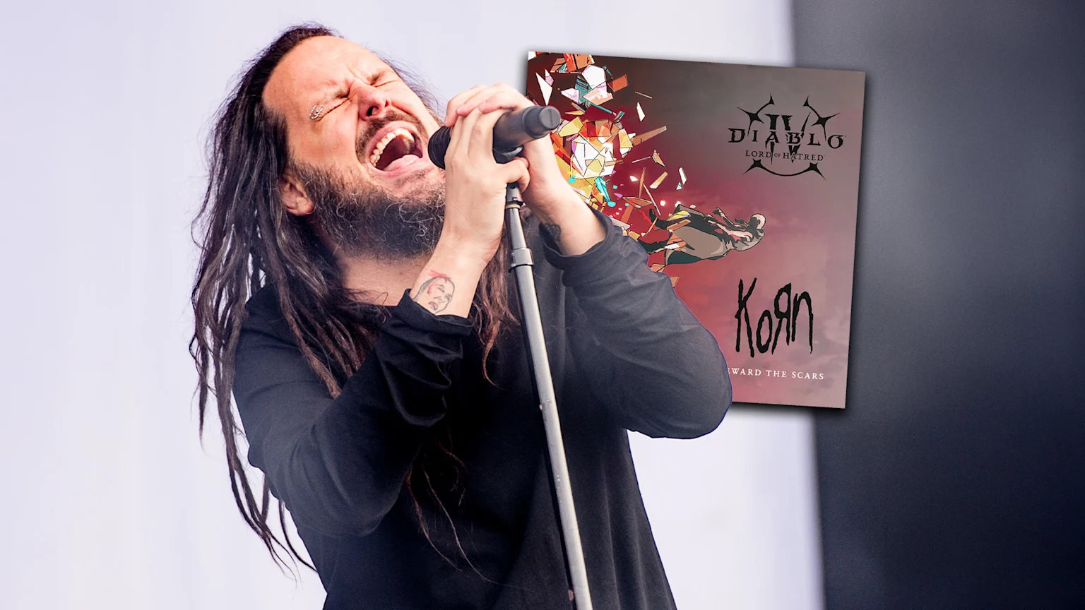 Jonathan Davis of Korn sings passionately into a microphone, with a poster showing "Diablo IV Lord of Hatred" and "KoЯn Reward the Scars" next to him.