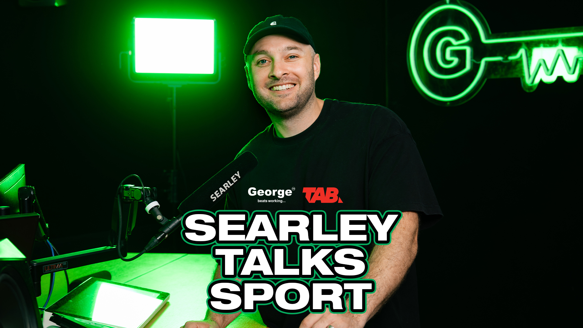 Searly in the George FM studio behind the mic. George Sports podcast logo with "Searley talks sport" with TAB logo above. 