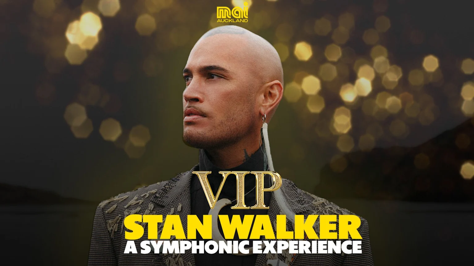A man, Stan Walker, wearing a textured jacket and an earring, looks left against a blurred background with golden bokeh lights. Text says "VIP STAN WALKER A SYMPHONIC EXPERIENCE".