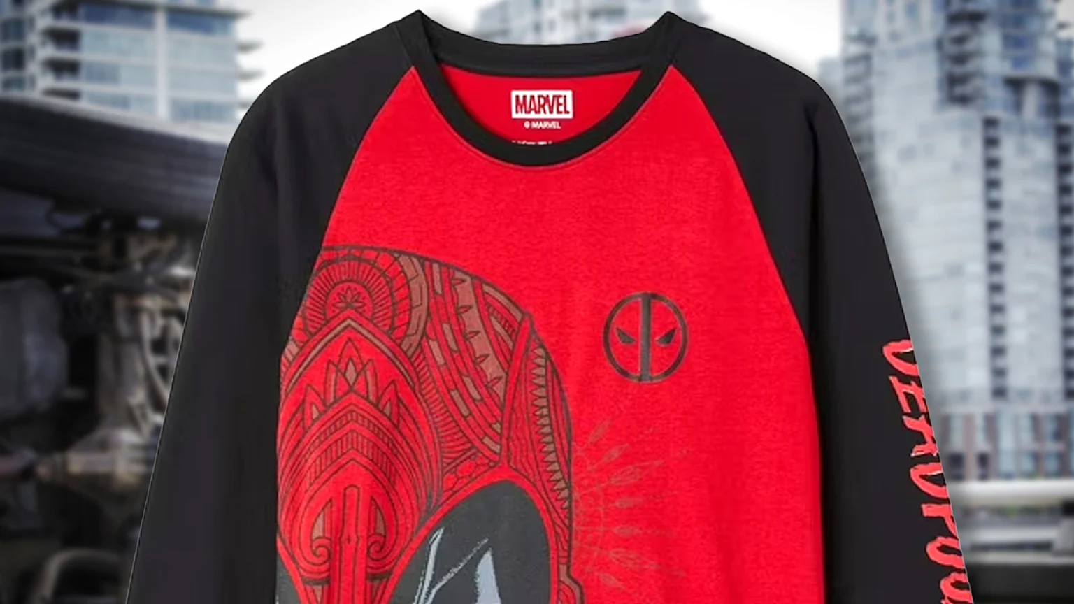 A red and black raglan Deadpool long-sleeve shirt displays a stylized Deadpool head with intricate patterns resembling a ta moko design, a circular Deadpool logo, and the name "DEADPOOL" vertically on the sleeve.
