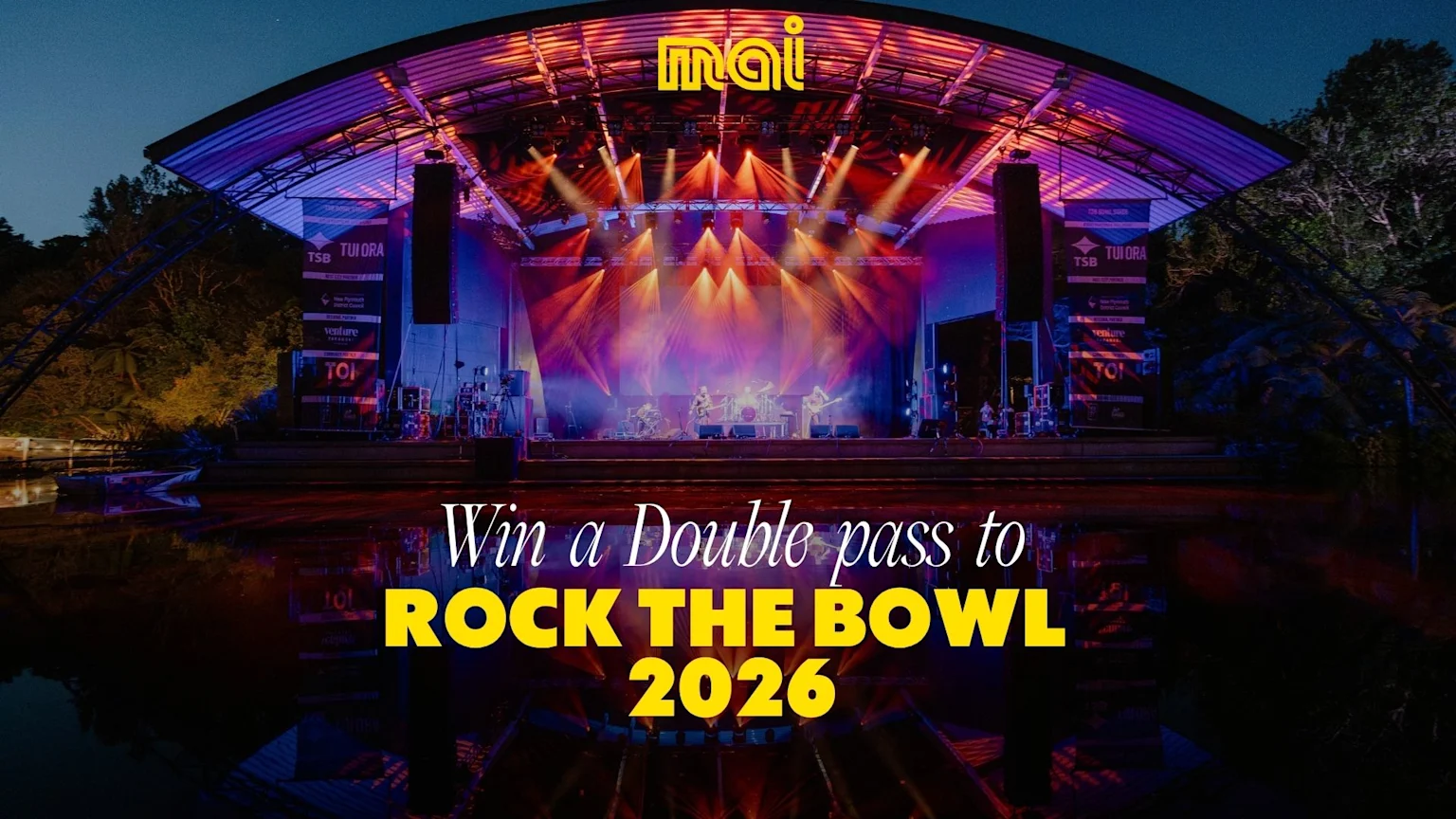 A band performs on an outdoor stage at night under colorful lights, with "Mai" branding and sponsor banners visible, and the overlaid text "Win a Double pass to ROCK THE BOWL 2026".