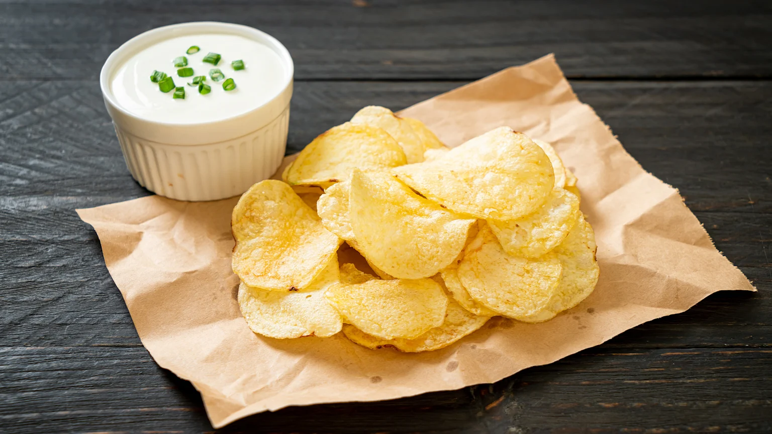 A picture of potato chips with sour cream.