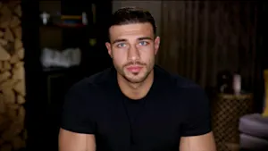 Tommy Fury sadly looking down a camera lens.