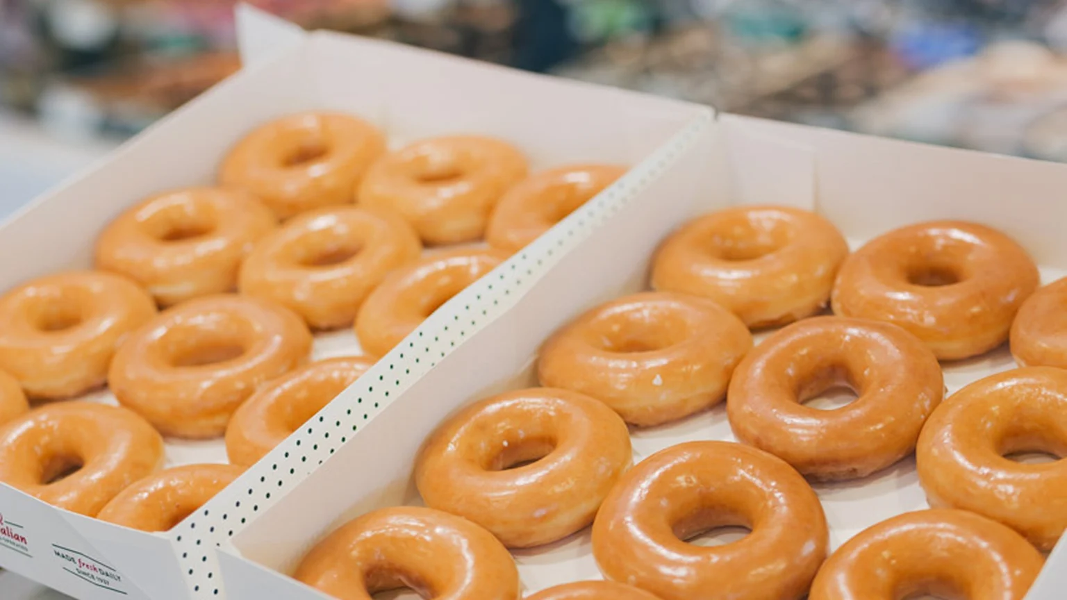 Two dozen glazed donuts in a white box