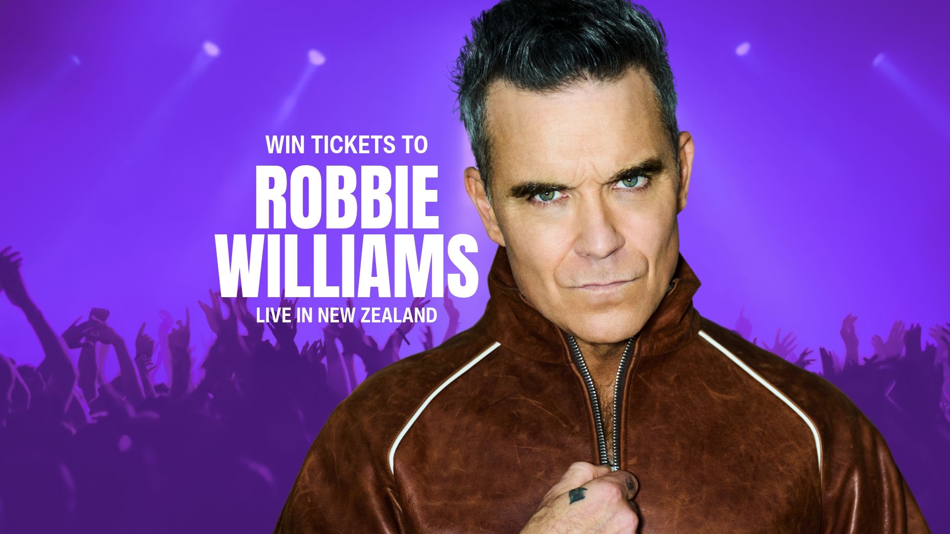 Robbie Williams in a brown leather jacket looks seriously at the camera, with text "WIN TICKETS TO ROBBIE WILLIAMS LIVE IN NEW ZEALAND" and a purple background with a crowd.