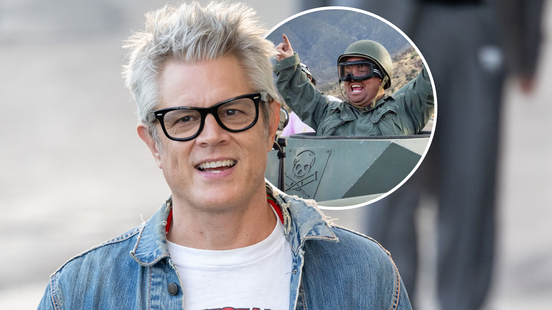 Johnny Knoxville, a smiling man with spiky grey hair and black-framed glasses, wears a denim jacket over a white t-shirt.