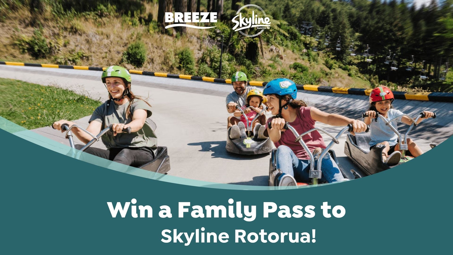 A smiling family of four, including two adults and two children in helmets, rides luge carts down a track at Skyline Rotorua on a sunny day.