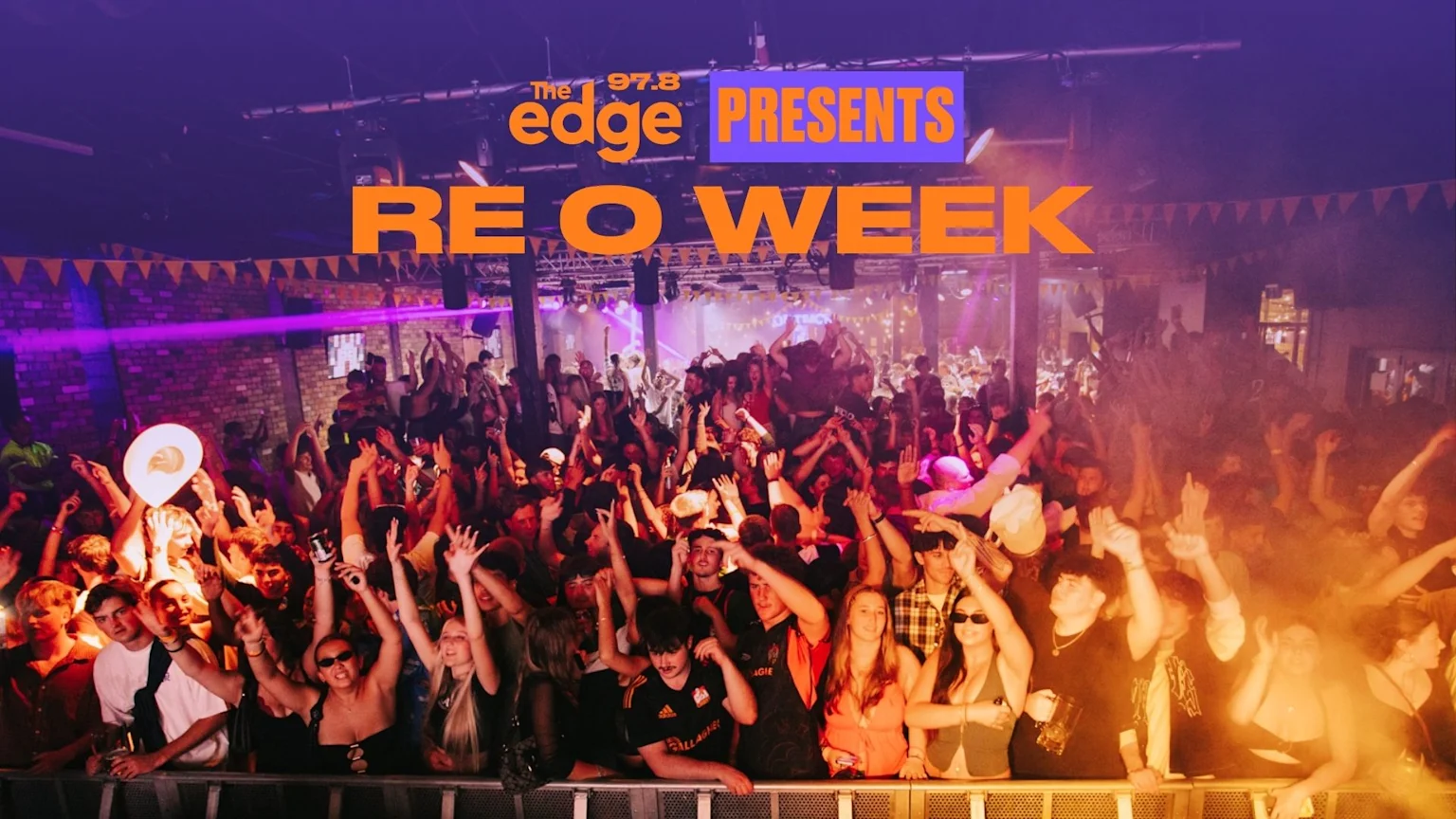 A large crowd of young people with hands raised in the air at a lively club or concert event with purple lights and smoke, overlaid with "The 97.8 edge PRESENTS RE O WEEK".