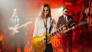 Cassie holding a guitar with two omre guitarists in the background