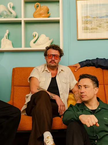 Bandmembers from Six60 pose on an orange couch.