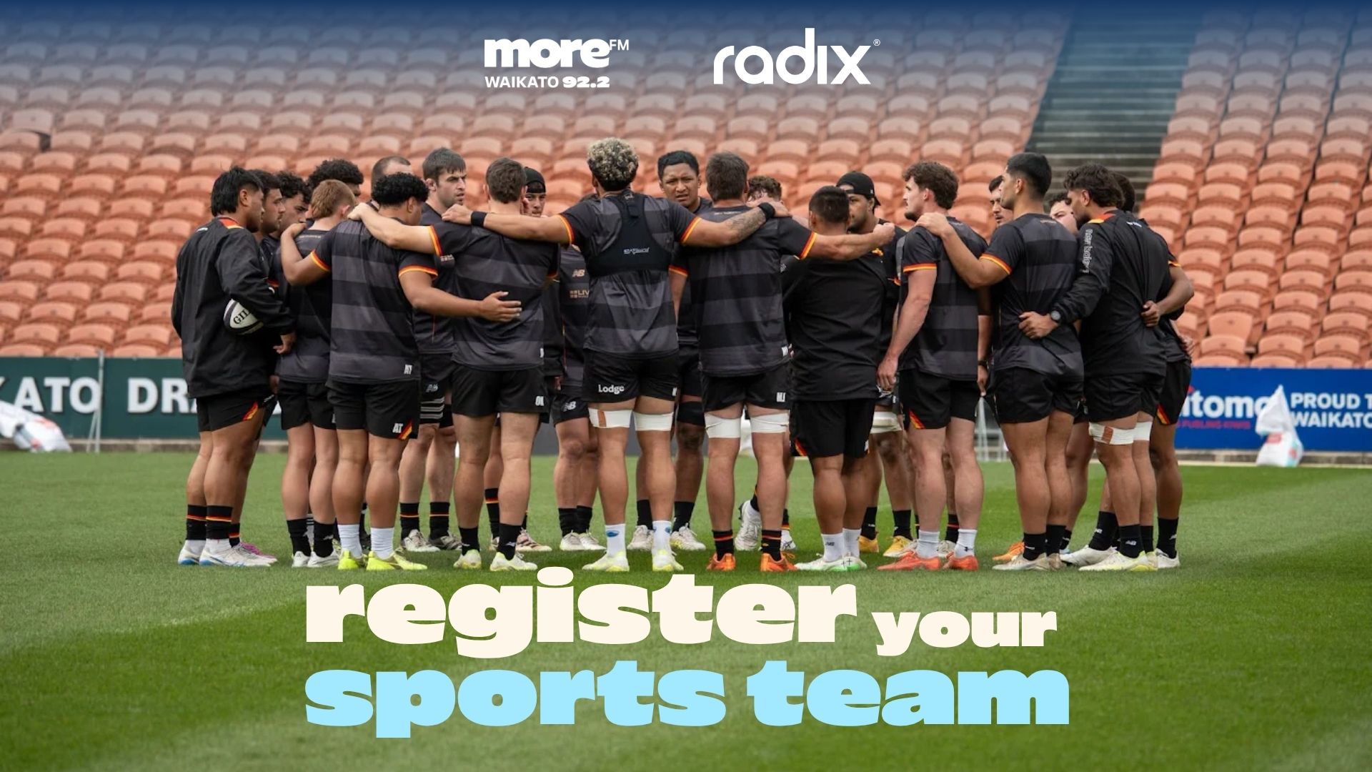 A group of rugby players in black and orange uniforms huddle on a field with a stadium in the background, beneath "moreFM" and "radix" logos, and text saying "register your sports team".