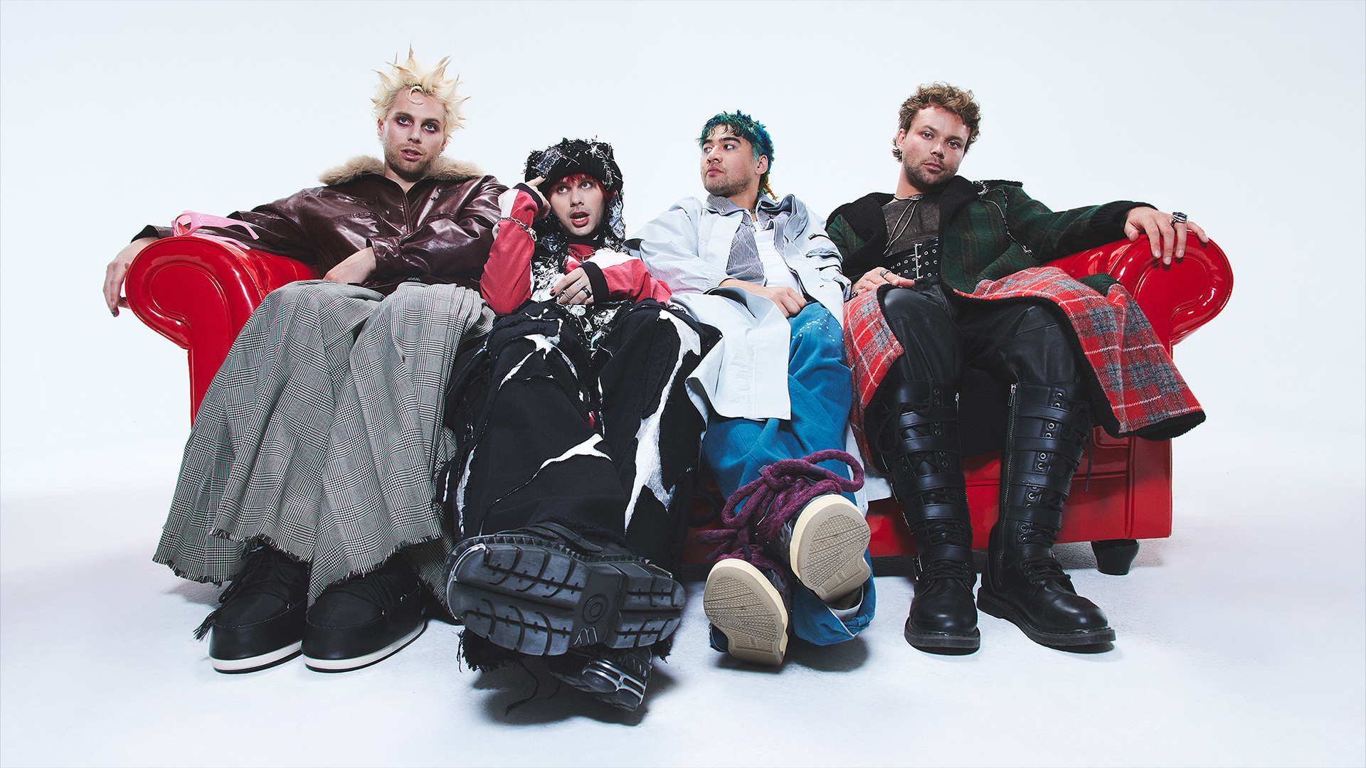 Band members from 5 Seconds of Summer sit casually on a bright red couch