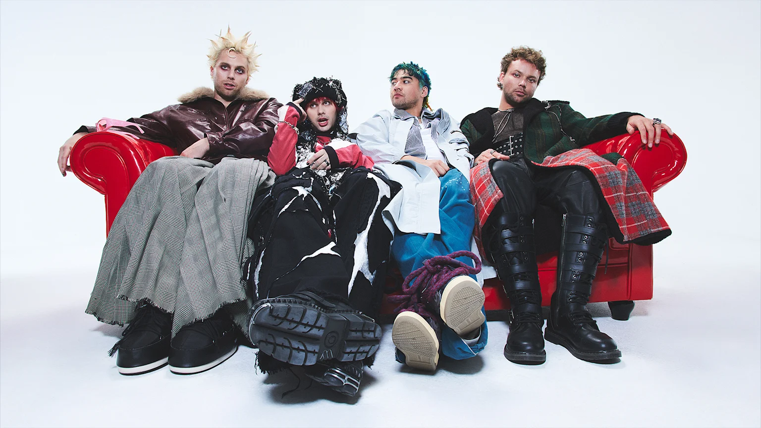 Band members from 5 Seconds of Summer sit casually on a bright red couch