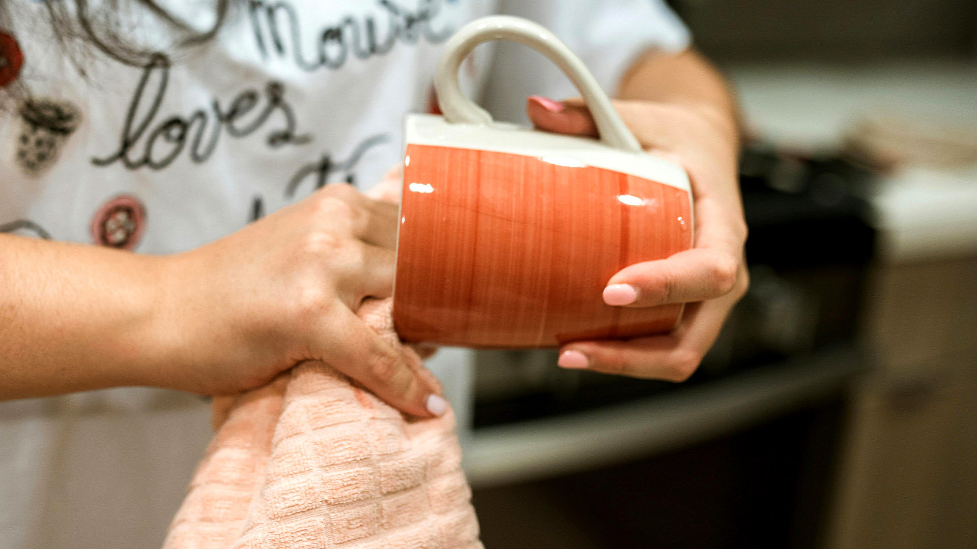 Woman drying a mug with a tea towel.