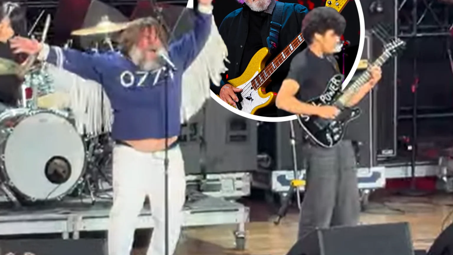 A singer in a blue shirt with a beard performs on stage with arms raised, next to a guitarist, while a circular inset shows an older man playing a gold bass guitar as a crowd watches.