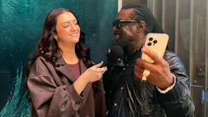 Reporter with microphone asking man a question while he holds up a phone