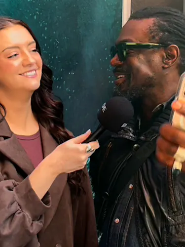 Reporter with microphone asking man a question while he holds up a phone