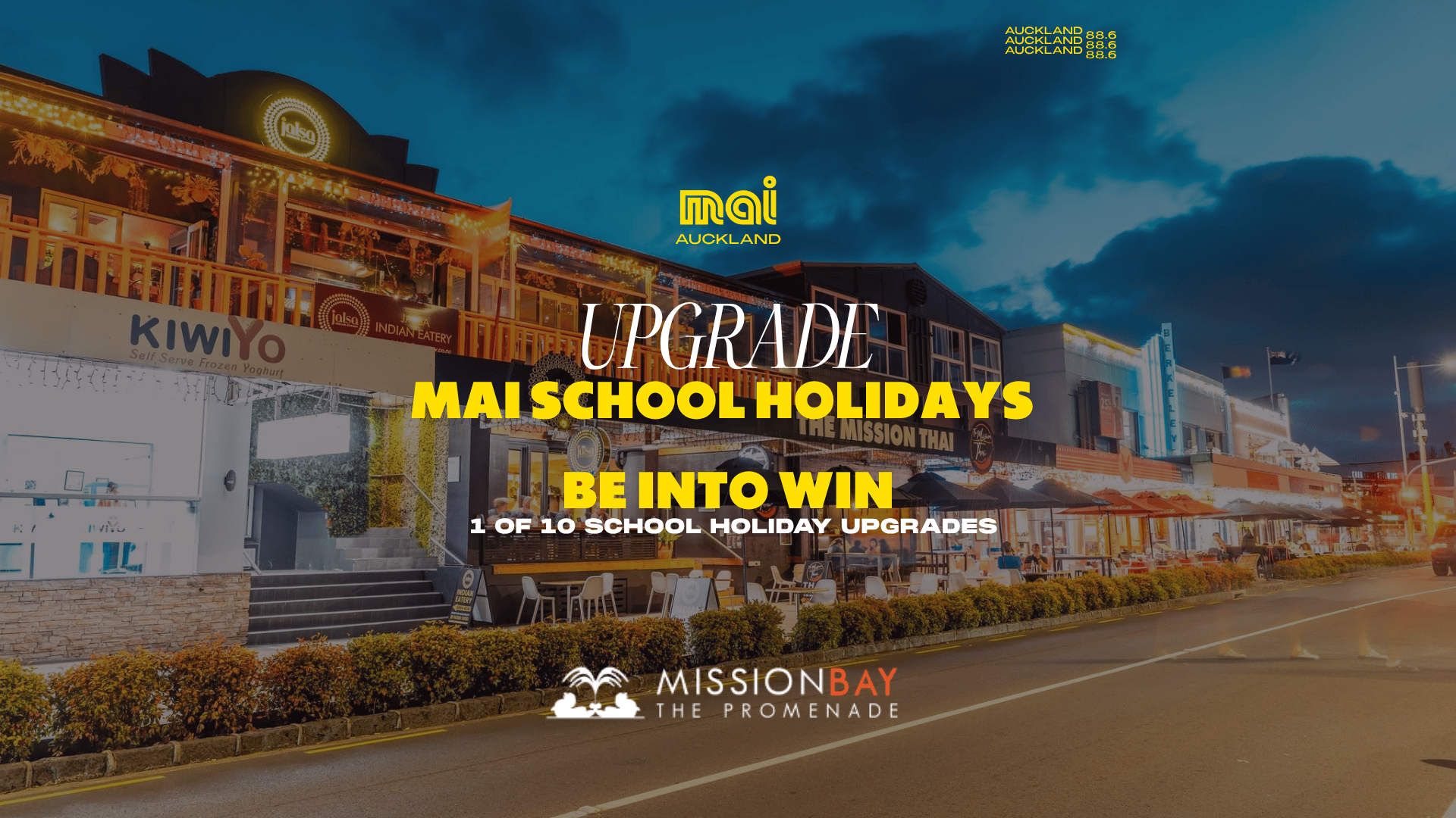 A vibrant night view of Mission Bay Promenade with illuminated restaurants and shops, featuring a prominent text overlay for "Mai School Holidays Upgrade."