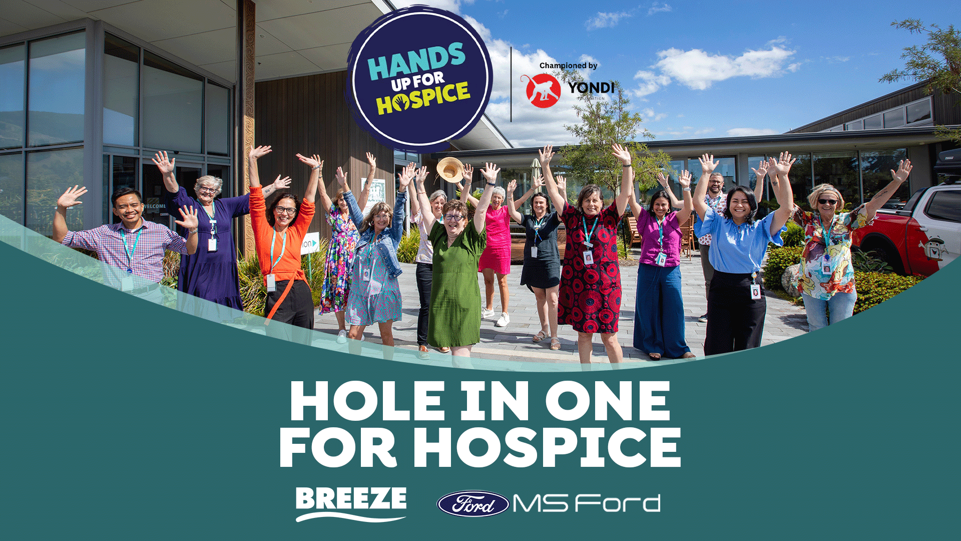 A large group of diverse adults stands outside a modern building with hands raised, smiling, next to "HANDS UP FOR HOSPICE" and "HOLE IN ONE FOR HOSPICE" text.