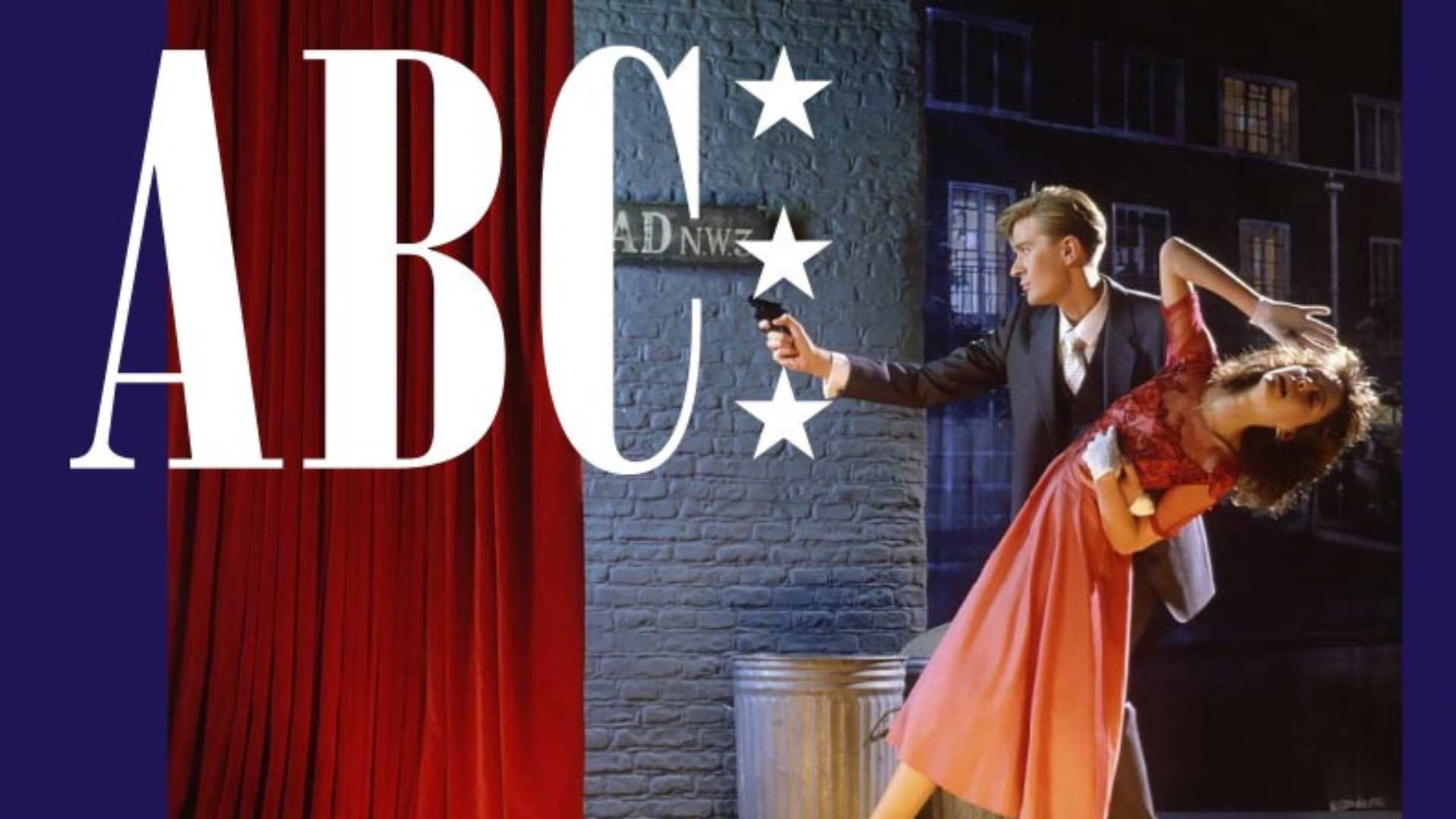 Large white "ABC" text overlays a scene with red curtains, a brick wall featuring a street sign and stars, and a man pointing a gun at a dramatically posed woman in a red dress.