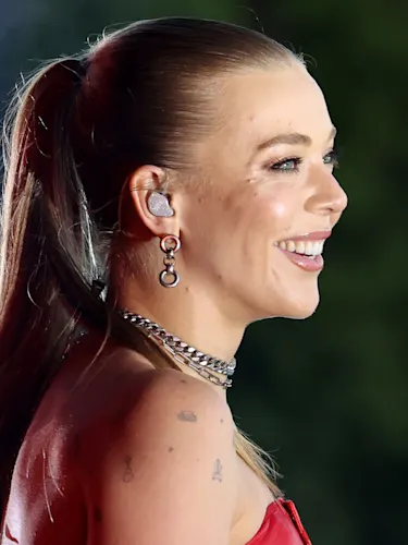 UK singer Becky Hill side profile looking to the right with a big smile.