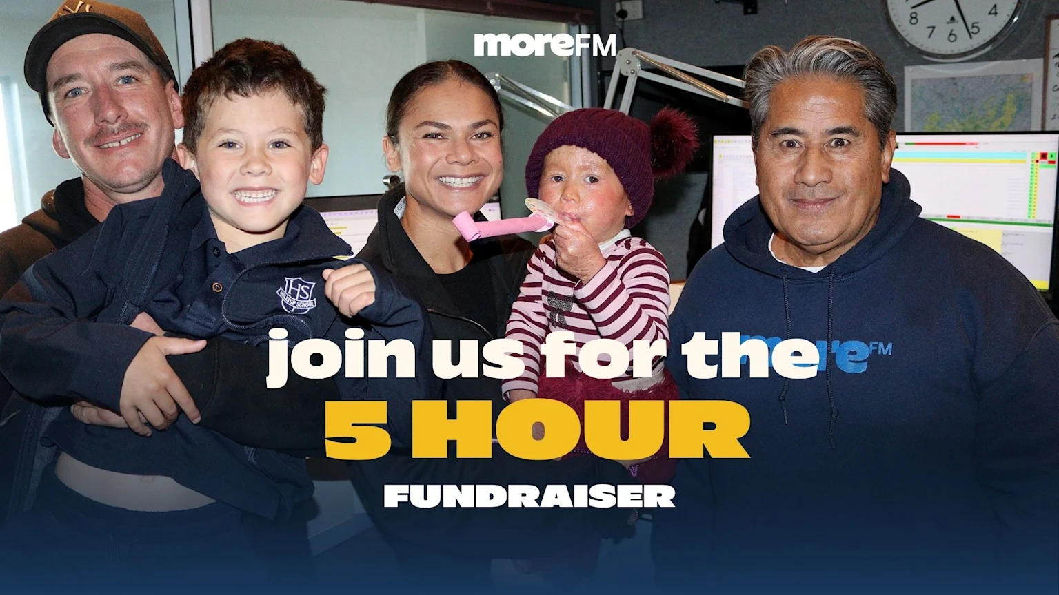 Smiling people in a More FM radio studio pose with a child with a visible skin condition blowing a party blower, and another boy, for a 5-hour fundraiser.