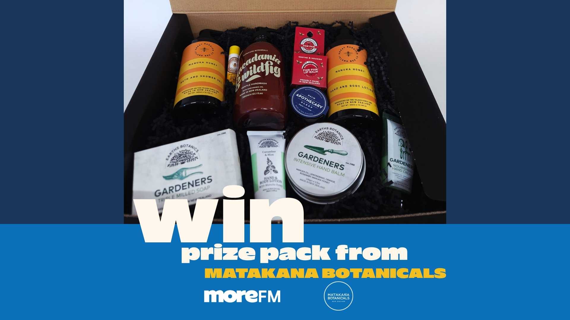 An open brown gift box filled with various skincare products including hand wash, lotions, balms, and soaps from Matakana Botanicals and Earth's Botanics, with overlaid text "Win prize pack from MATAKANA BOTANICALS moreFM".