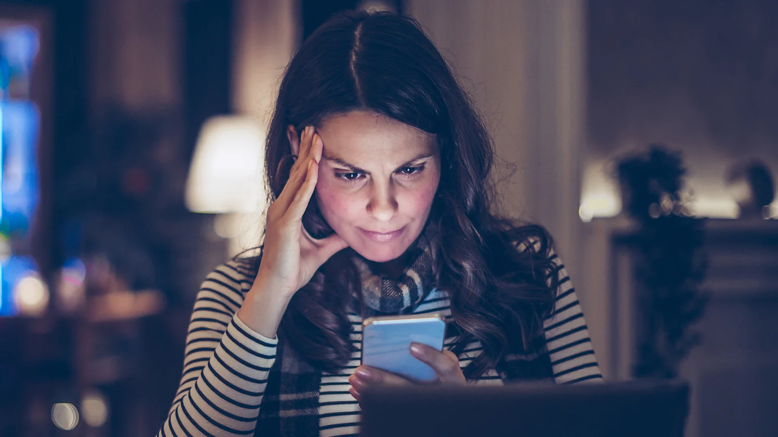 Woman looking at her cell phone screen as if she's asked it a question and reading the answer.