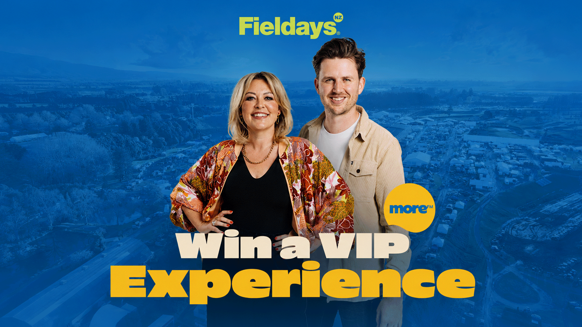 A smiling woman and man stand in front of a blue-toned aerial view of an outdoor event, with "Fieldays NZ" and "more FM" logos, and "Win a VIP Experience" text.