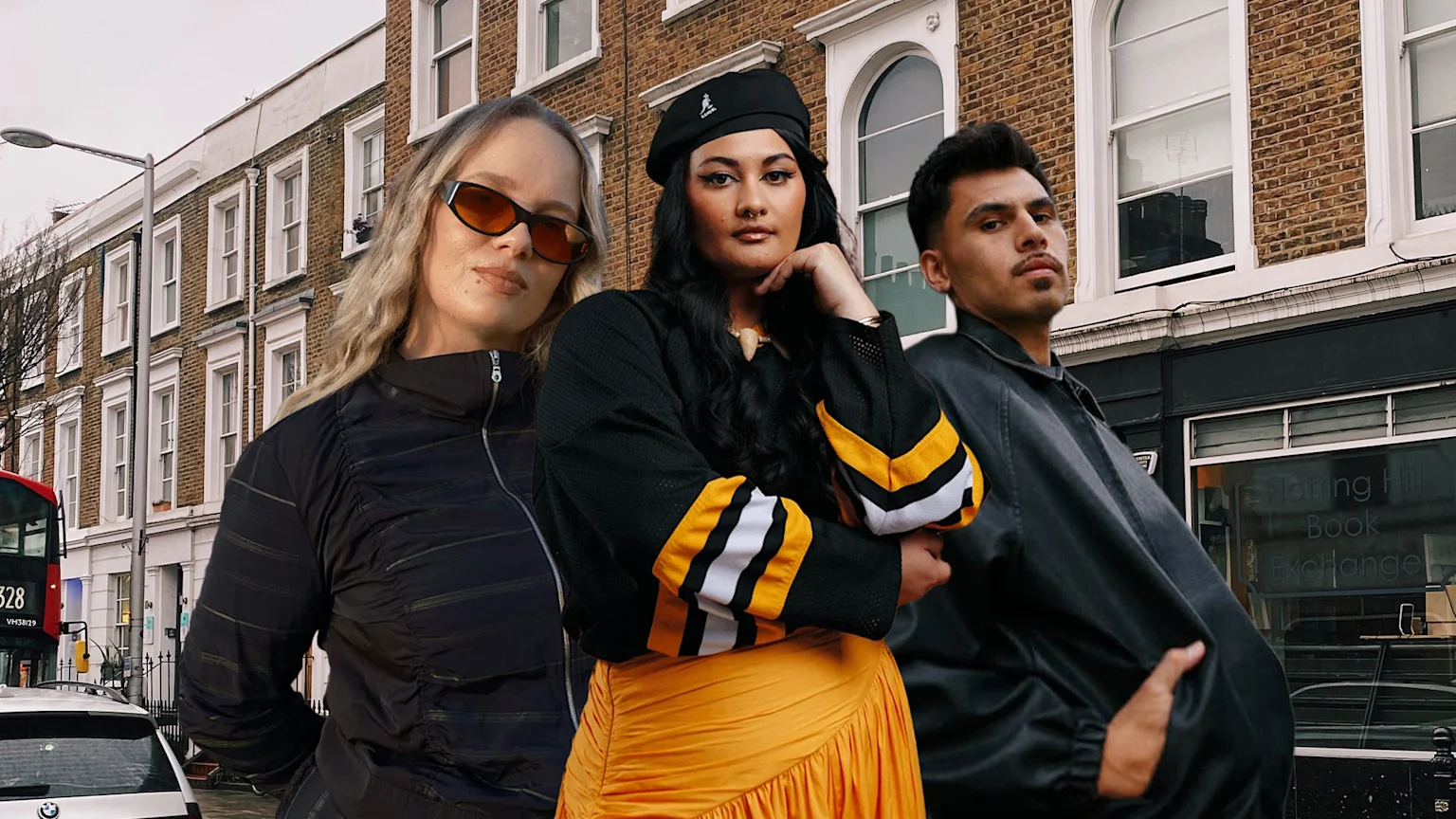 Three people, two women and one man, stand posing on a street with brick buildings and a "Notting Hill Book Exchange" sign in the background. A red bus is on the left.