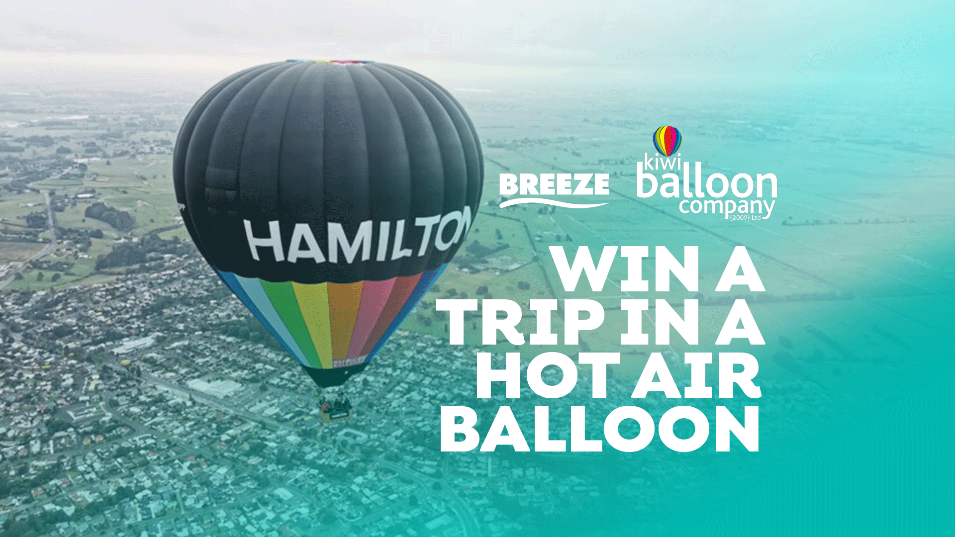 A black hot air balloon with "HAMILTON" written on it and a rainbow lower section flies over a city, with "WIN A TRIP IN A HOT AIR BALLOON" text and sponsor logos.