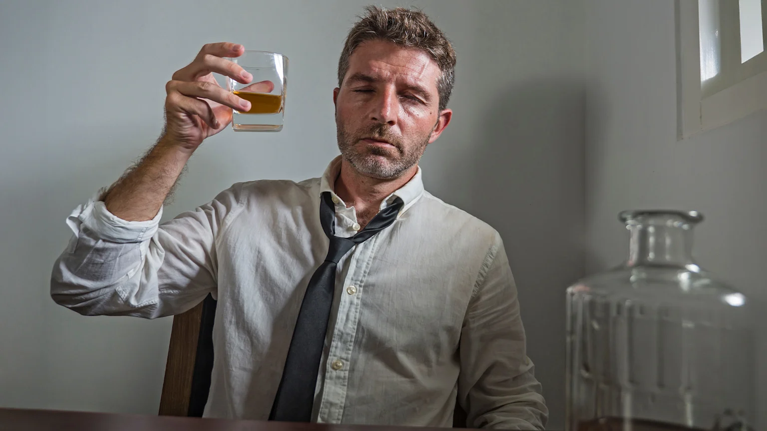 Man looking rough while drinking alcohol.