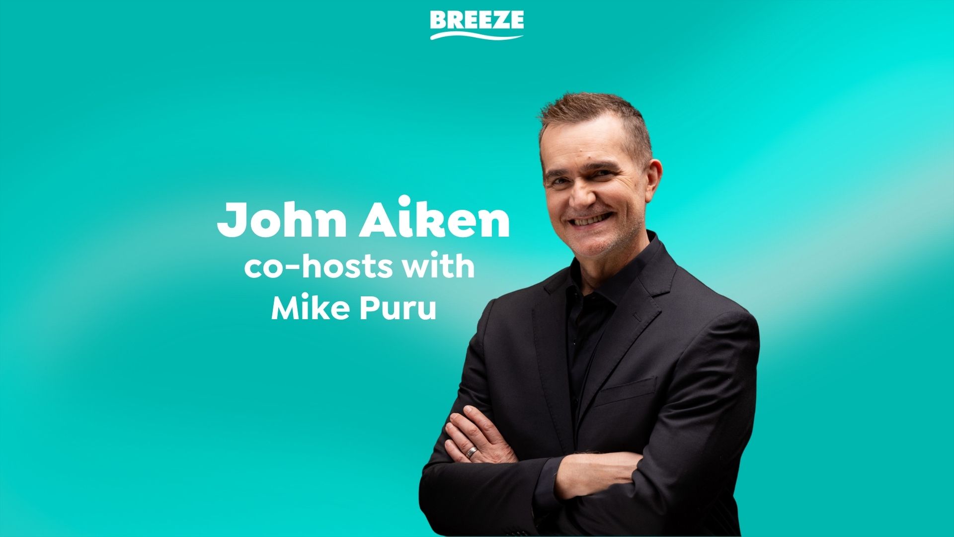 A smiling John Aiken, wearing a black suit with crossed arms, stands against a teal background, next to text that reads "John Aiken co-hosts with Mike Puru" and the "BREEZE" logo.