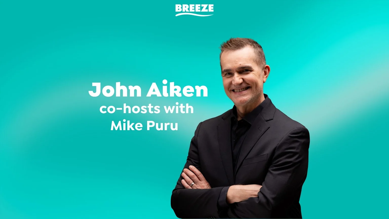 A smiling John Aiken, wearing a black suit with crossed arms, stands against a teal background, next to text that reads "John Aiken co-hosts with Mike Puru" and the "BREEZE" logo.