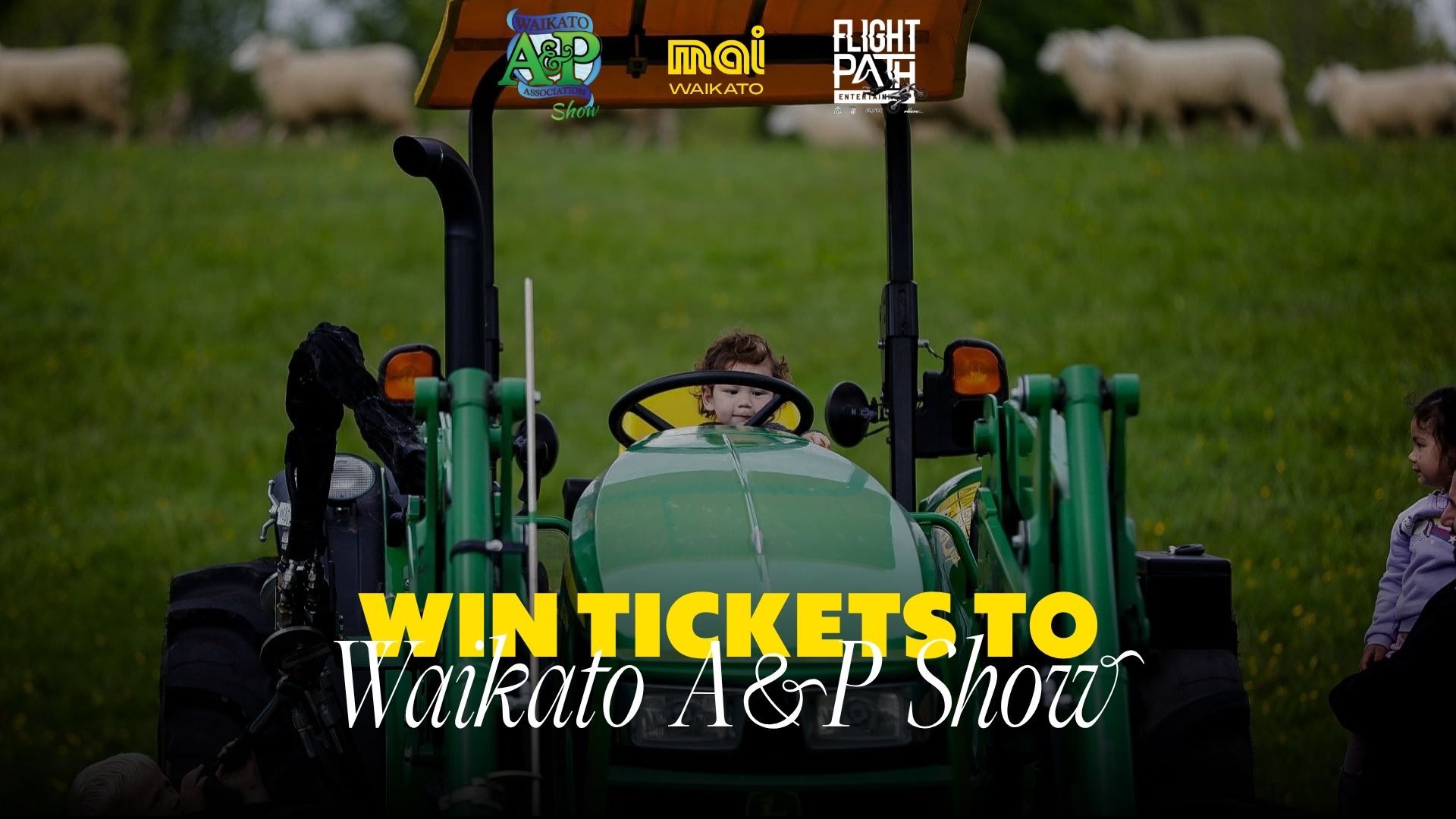 A child sits in a green tractor in a field with sheep and another child, with logos for Waikato A&P Show, Mai Waikato, and Flight Path Entertainment visible at the top.