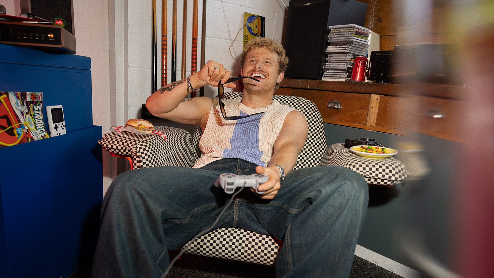 Man sitting on a couch laughing with a controller in hand