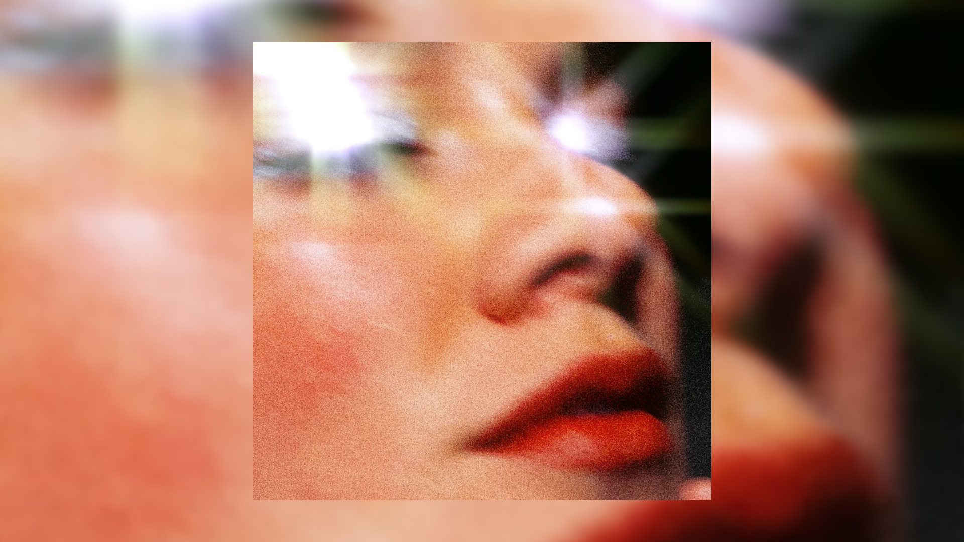 Close-up of a person's face from nose to chin with red lips and warm skin tones, featuring bright lens flares around the eyes and a grainy texture, set against a dark background.