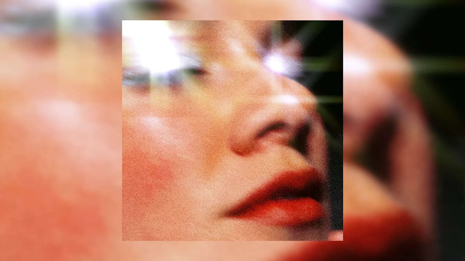 Close-up of a person's face from nose to chin with red lips and warm skin tones, featuring bright lens flares around the eyes and a grainy texture, set against a dark background.