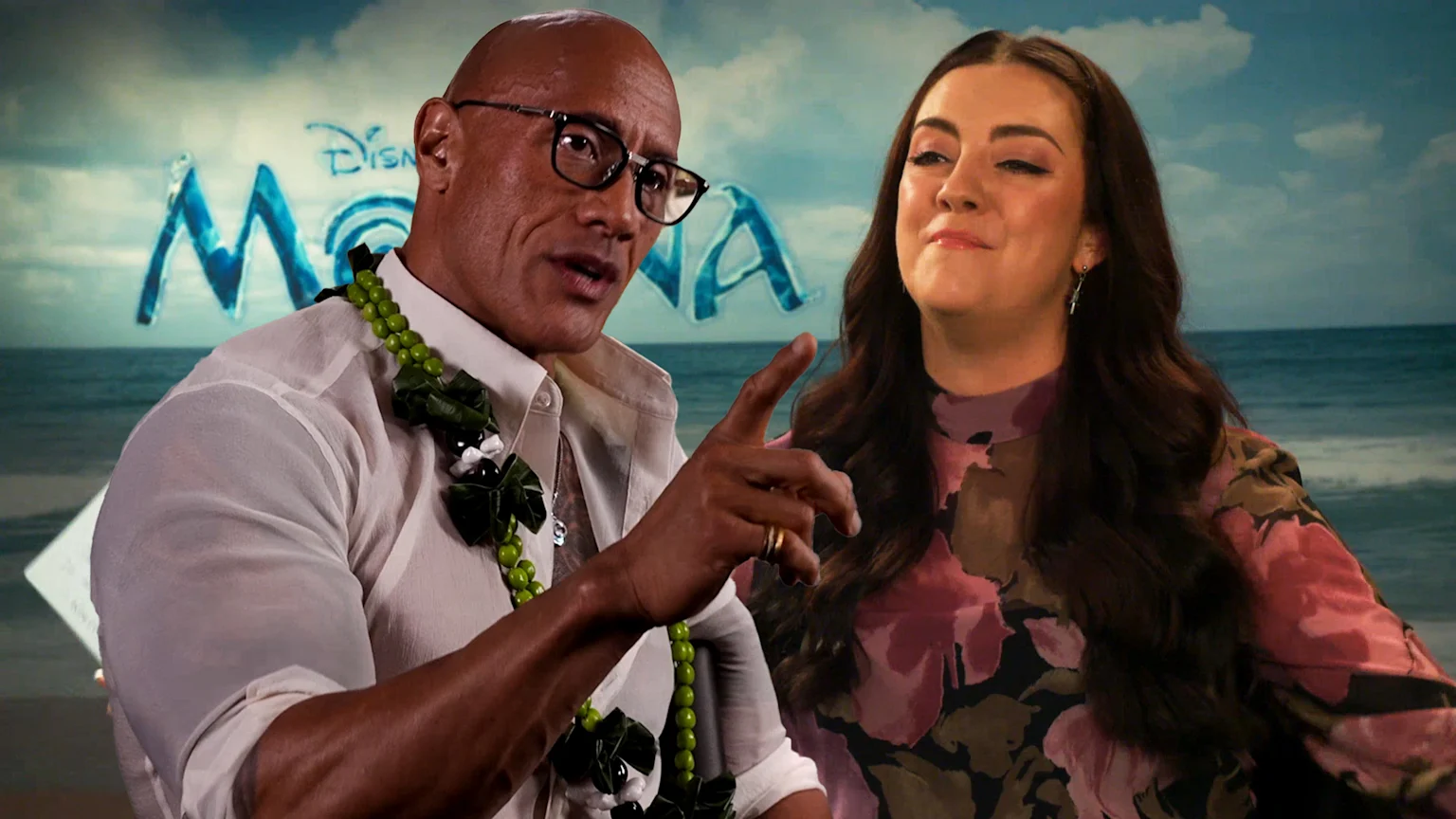 Dwayne "The Rock" Johnson, in a white shirt and lei, points while a woman in a floral dress looks on, against a Disney Moana backdrop.
