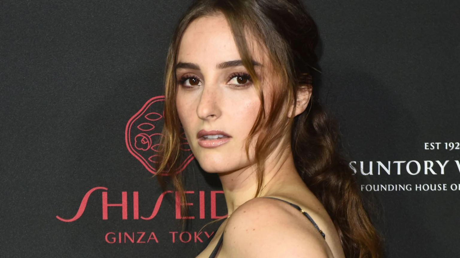 A woman with long brown hair and light makeup looks to her left, with the logos "SHISEIDO GINZA TOKYO" and "SUNTORY WHISKY" visible on a dark background.