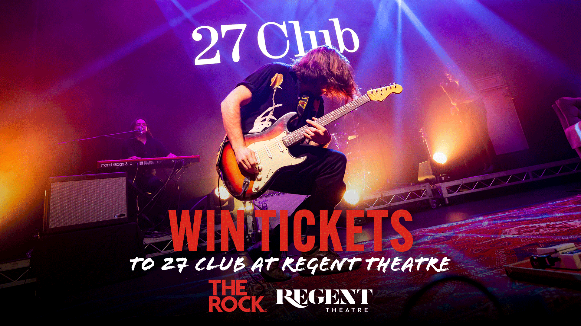 The 27 Club rock band performs on stage, with a lead guitarist playing an electric guitar in the foreground and a keyboardist behind him, surrounded by bright stage lights and promotional text.