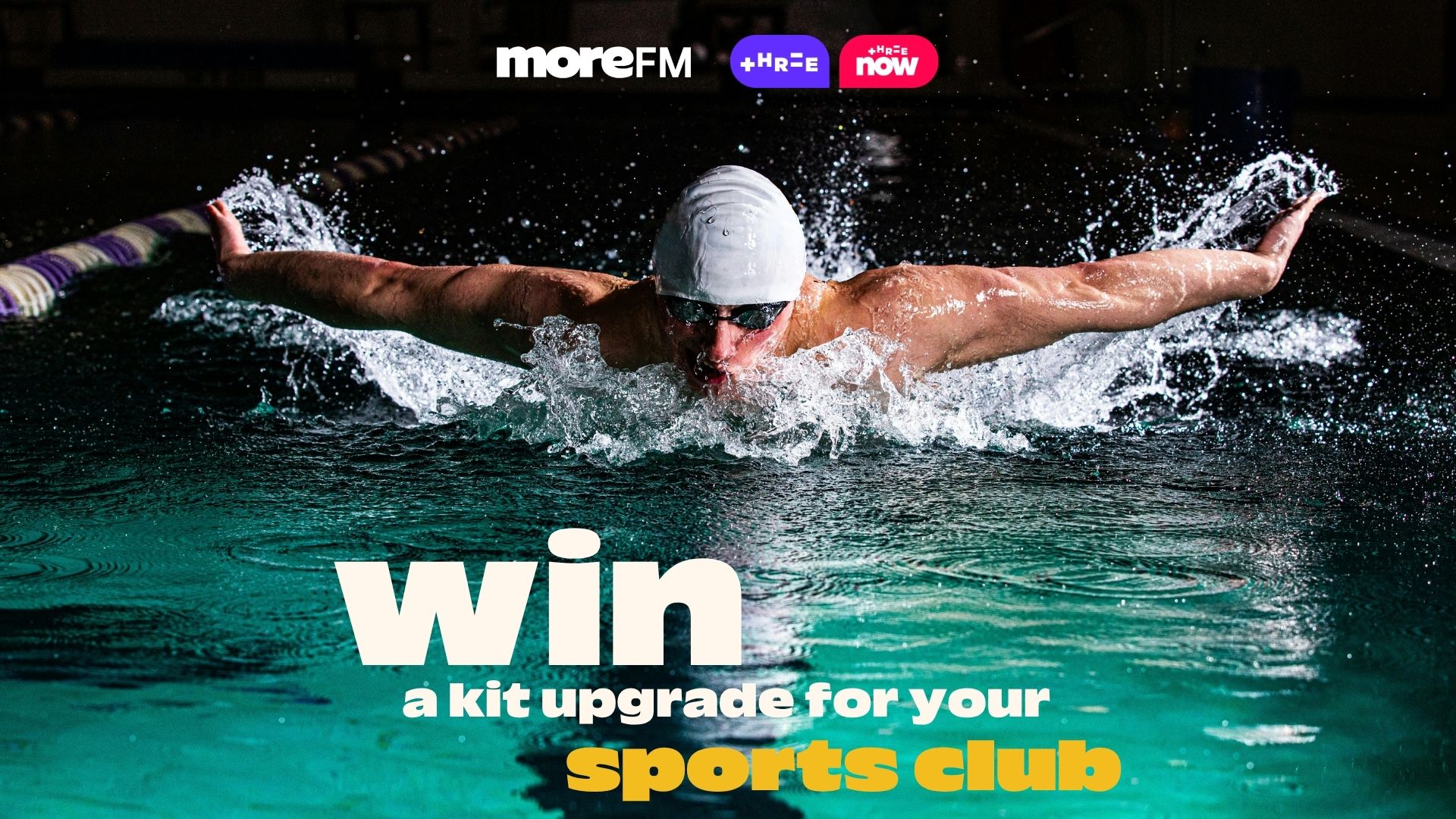 A swimmer performs the butterfly stroke in a pool with water splashing, beneath logos for moreFM and Three, promoting "win a kit upgrade for your sports club."