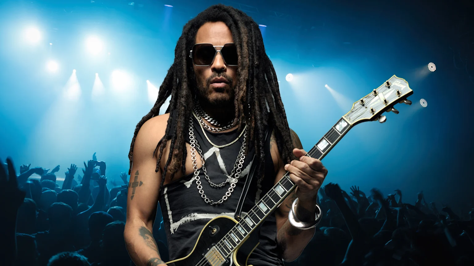 Lenny Kravitz stands in front of concert crowd holding a guitar