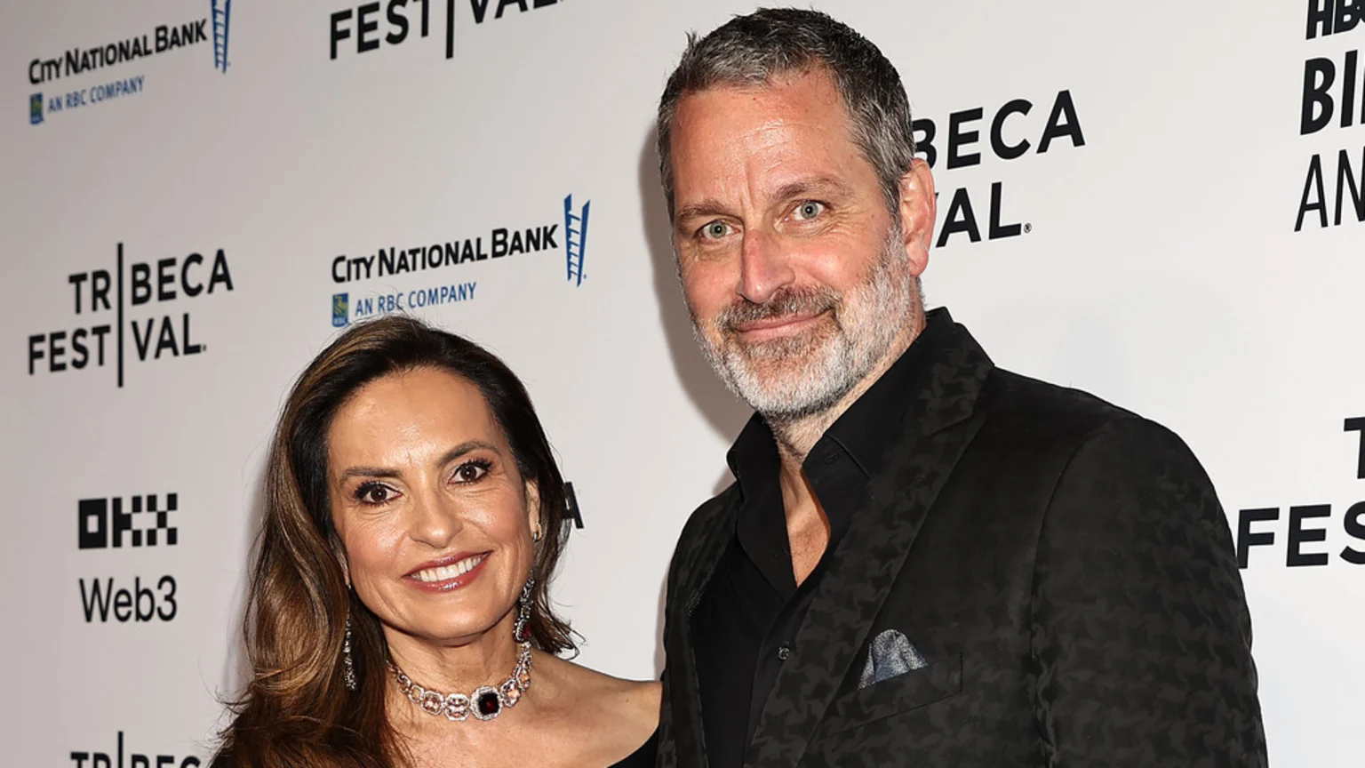 A smiling woman with brown hair and a man with a grey beard pose for a photo at an event, with "Tribeca Festival" logos visible in the white background.