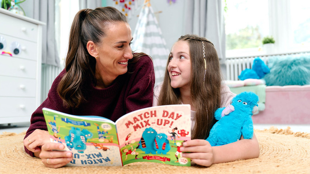 A smiling woman and a young girl lie on a rug, looking at each other as the woman holds an open children's book titled "MATCH DAY MIX-UP!".