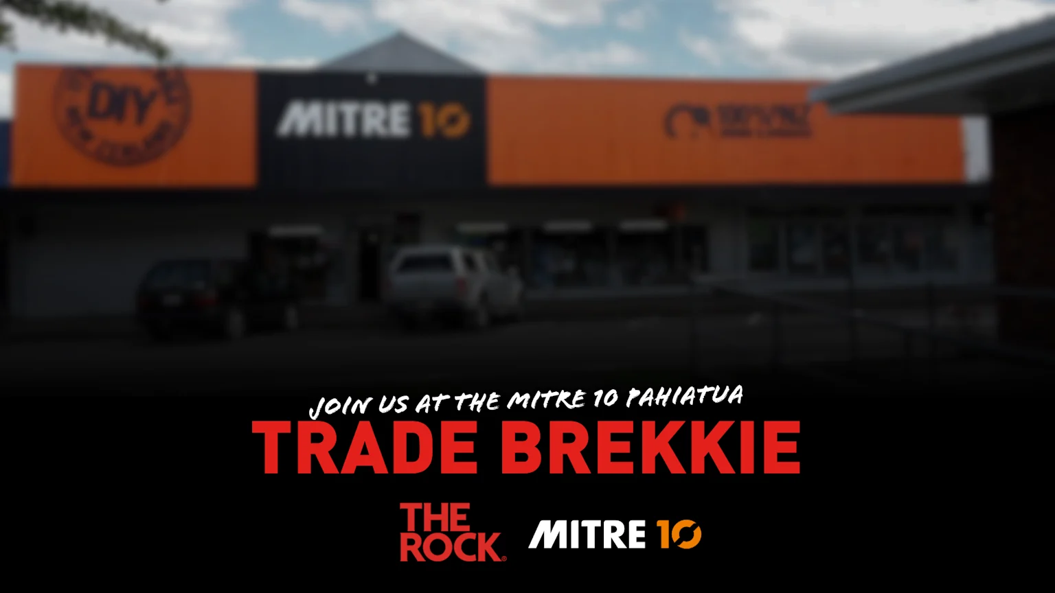 A blurred exterior shot of a Mitre 10 store in Pahiatua with overlay text inviting to a "Trade Brekkie" and showing "The Rock" and "Mitre 10" logos.