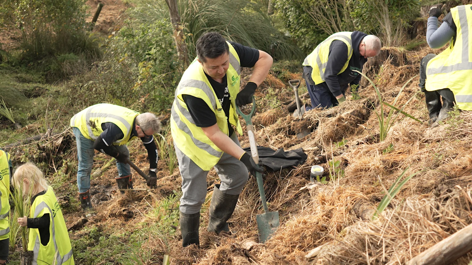 The Breeze's Mike Puru and tree-planting volunteers in hi-vis planting on hillside