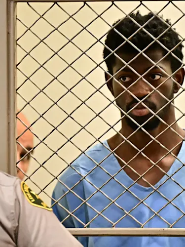 Lil Nas X behind barred door looking at an LA police officer.